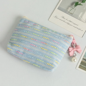 Detail of light blue tweed cosmetic bag with pink bow and pearl zipper pendant