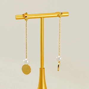 Elegant gold tassel earrings with white pearls and round geometric charms on a T-stand