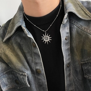 Detailed view of silver sunburst pendant necklace with spiral center on a black top