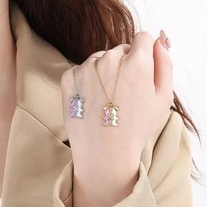 Detail of bear pendant necklace with cross design in gold and silver finish