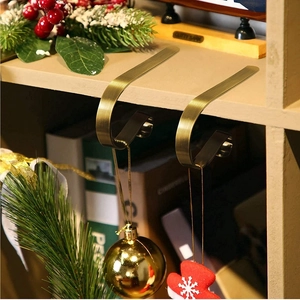Golden metal Christmas stocking hooks for mantel decor with festive pine and berry accents