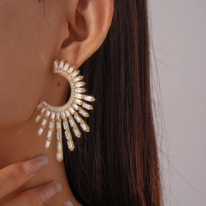 Close-up of gold C-shaped earrings with rectangular zircons worn by a model