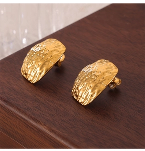 Gros plan sur des boucles d'oreilles en acier titane doré au design martelé unique