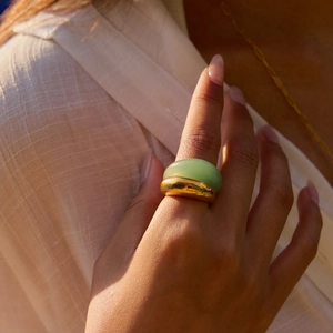 Dettaglio ravvicinato di un anello dorato con pietra naturale verde sulla mano