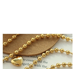 Detailed close-up of a 18K gold plated heart pendant necklace with beaded chain