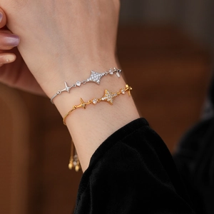 Detail of adjustable star charm bracelets in gold and silver with sparkling zircon stones