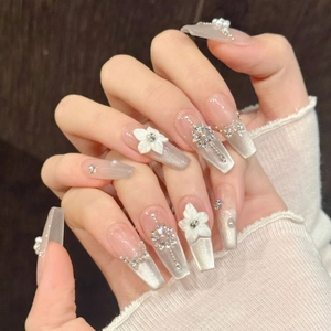 Détails d'ongles cat-eye argentés avec fleurs 3D blanches et strass brillants décoratifs