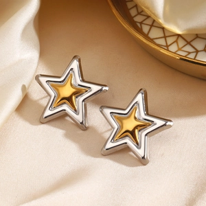 Fashionable two-tone star stud earrings with silver and gold finish on beige silk fabric