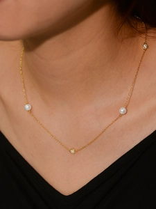 Close-up of golden necklace with white freshwater pearls and cubic zirconia on neck