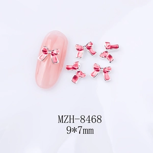 Nail art nœud en émail rose avec bordure en métal, détail de 9x7mm sur fond blanc