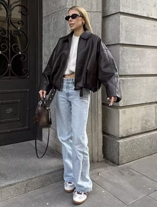 Full street style view of a black leather bomber jacket with light blue denim jeans