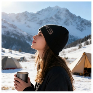 Dettaglio del berretto in maglia nera con logo HEAD dorato su uno sfondo di montagne innevate