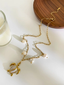 Detail of gold titanium turtle pendant with sea shell inlay and white freshwater pearls
