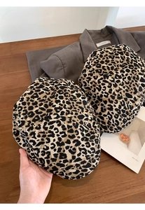 Flat lay of vintage leopard print beret hats on a wooden table with fashion magazines