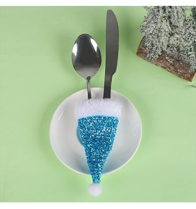 Blue sequin Christmas hat cutlery holder with white fur trim on a plate with silverware
