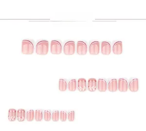Detail of short square press-on nails with nude pink french tips and leaf patterns