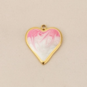 Close-up of heart pendant with gold border and pink white swirl enamel texture