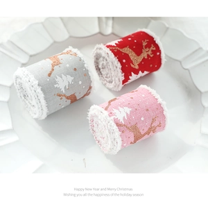 Close-up of Christmas ribbon rolls with gold reindeer patterns and white plush edges