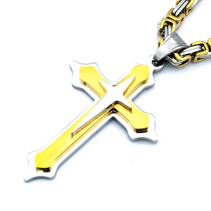 Gros plan détaillé d'un pendentif croix triple couche bicolore en acier inoxydable avec chaîne
