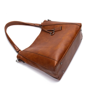 Detail of tan vintage leather tote showing gunmetal hardware and side rivet accents