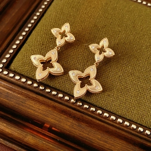 Macro shot of gold-plated rhombus flower earrings with brushed texture and zircon stones