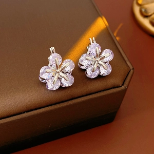Vue macro des boucles d'oreilles fleurs en zircon argenté avec pierres mauves sur boîte