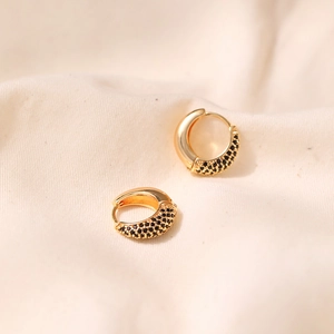 Macro shot of 18K gold plated brass hoop earrings with black zircon pavé on beige fabric