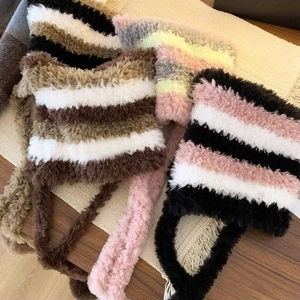 Flat lay of colorful striped plush beanies on a wooden table with neutral background