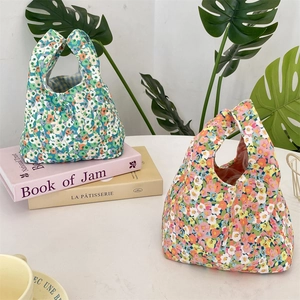 Detailed view of floral corduroy wrist bags in blue and pink on a stylish white desk
