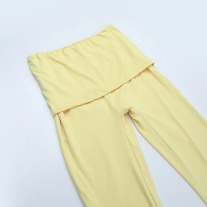 Detail der elastischen hellgelben Strickhose mit weitem Bein und hohem Bund