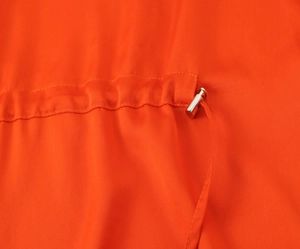 Detail of orange satin fabric featuring a drawstring and silver metallic cord stopper