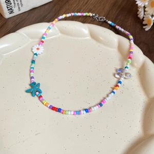 Detailed close-up of colorful beaded necklace with starfish and floral charms on a tray
