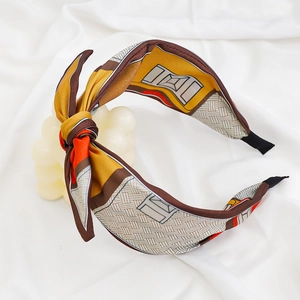 Detail of floral print wide headband with decorative bow knot in ginger and brown colors