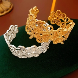 Detailansicht von Gold- und Silberarmreifen mit Blumenmuster auf grünem Samthintergrund