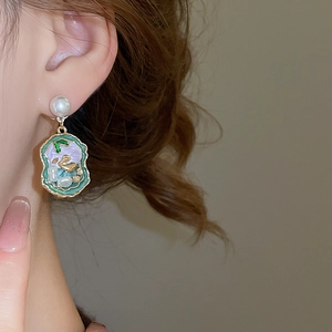 Detailed close-up of retro enamel pearl drop earrings featuring a gold swan motif