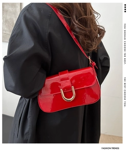 Detail of red patent leather shoulder bag with a gold U-shaped magnetic buckle