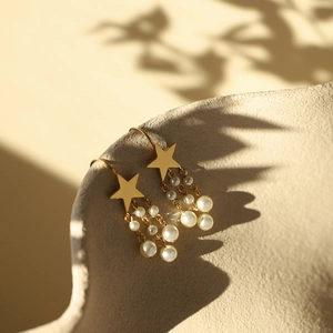 Macro shot of gold star pearl tassel earrings with fine dangling chain details