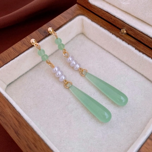 Detail of vintage teardrop earrings with green resin beads and white pearls on velvet