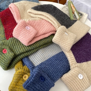Macro shot of colorful chunky knit Balaclava hats with decorative buttons for winter