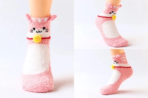 Close-up of pink and white coral fleece socks featuring 3D cat design and yellow bell detail