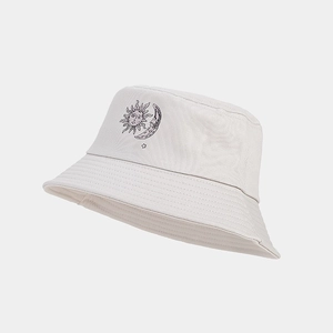 Detail view of cream canvas bucket hat showing embroidered sun and moon graphics