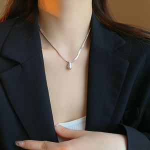 Detailed close-up of a silver water drop pendant necklace on a snake chain