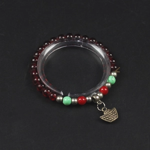 Red and green beaded bracelet with gold ingot pendant on transparent display stand