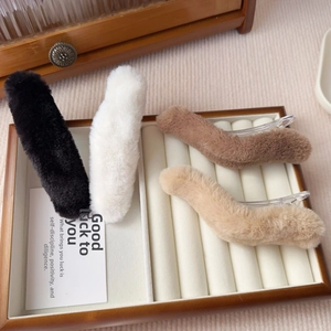 Set of four plush faux fur hair clips in black, white, brown, and beige on a tray