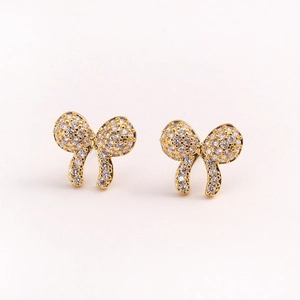 Detailed close-up of golden bow earrings featuring sparkling clear cubic zirconia stones