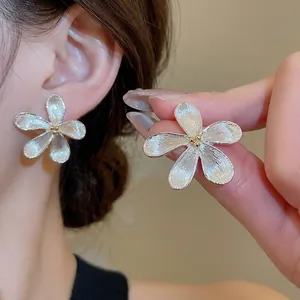 Orecchini a fiore in metallo spazzolato dal design minimalista indossati da una modella
