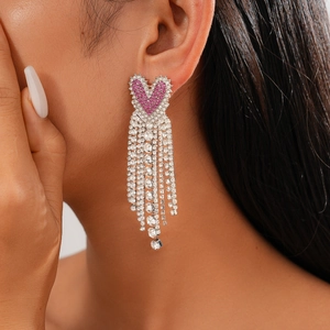 Close-up of pink heart tassel earrings with silver rhinestones worn by a model