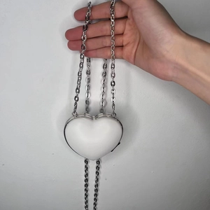 Detailed view of heart-shaped white sequin evening bag with silver metal chain straps