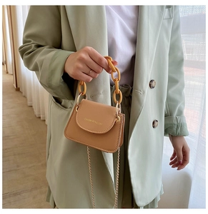 Close-up of khaki mini jelly bag with thick ginger top handle and gold chain strap