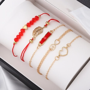 Gros plan d'un ensemble de 5 bracelets rouges et dorés sur un coussin à bijoux